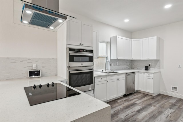 kitchen with sink, white cabinetry, backsplash, stainless steel appliances, and light hardwood / wood-style floors