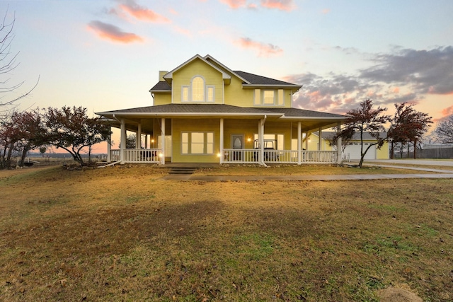 farmhouse featuring a porch, a yard, and a garage