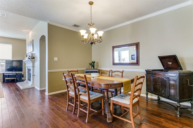 dining room featuring ornamental molding, dark hardwood / wood-style floors, a textured ceiling, and a notable chandelier