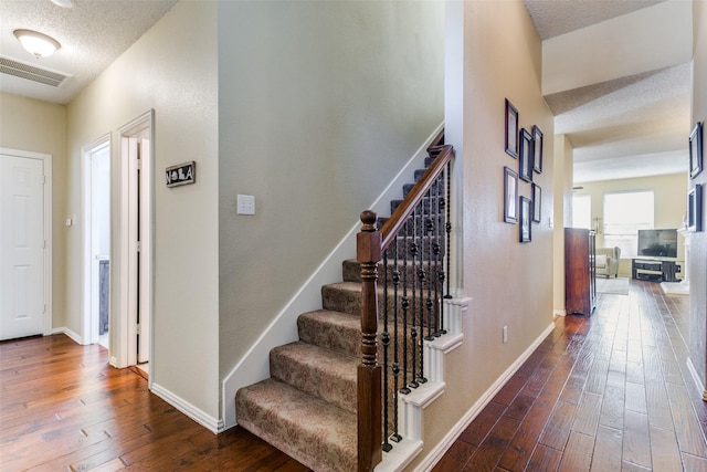 stairs featuring hardwood / wood-style flooring and a textured ceiling