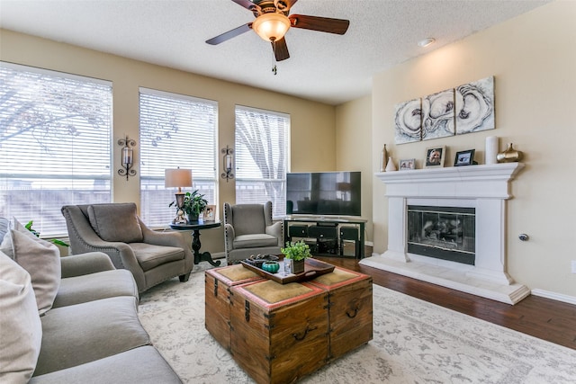 living room with ceiling fan, a textured ceiling, and light wood-type flooring