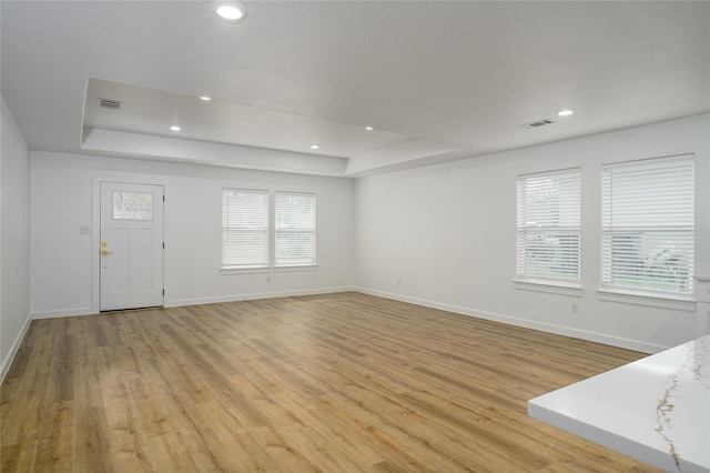 entrance foyer with a tray ceiling and light hardwood / wood-style floors