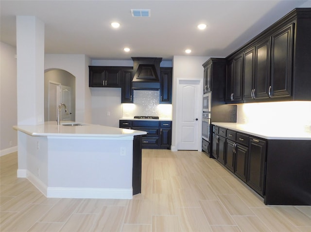 kitchen with premium range hood, appliances with stainless steel finishes, sink, and decorative backsplash