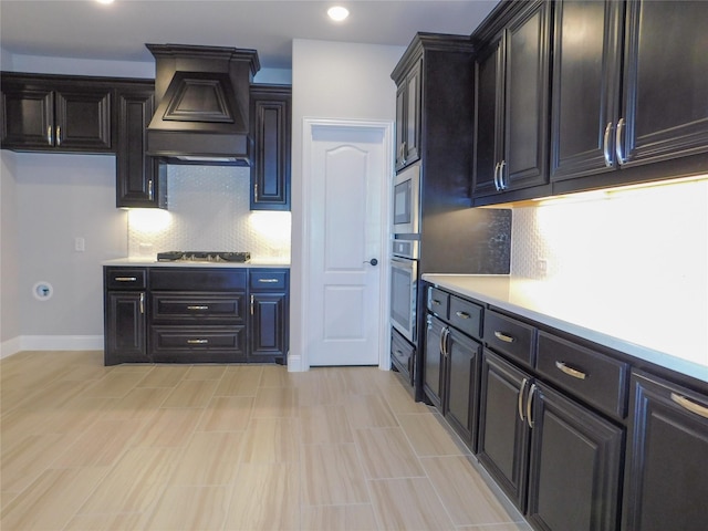 kitchen with premium range hood, built in microwave, backsplash, stainless steel oven, and gas stovetop