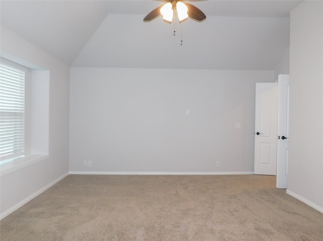 empty room with vaulted ceiling, light colored carpet, and ceiling fan