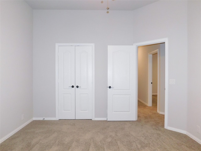 unfurnished bedroom with light carpet and a closet