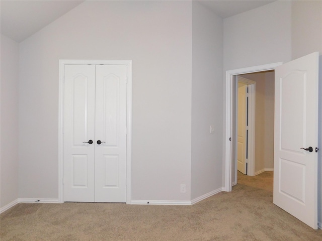 unfurnished bedroom with lofted ceiling, light carpet, and a closet