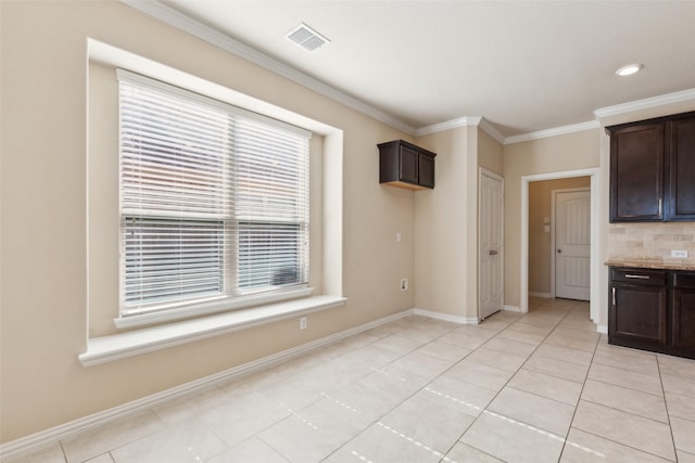 kitchen with crown molding, light stone countertops, light tile patterned floors, and dark brown cabinetry