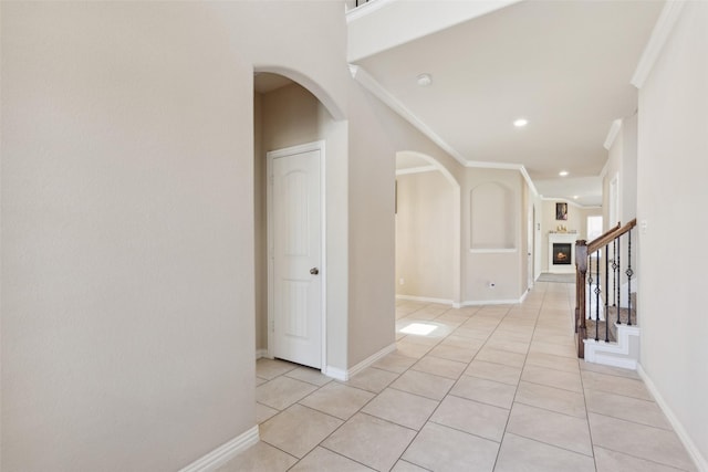 hall with ornamental molding and light tile patterned floors