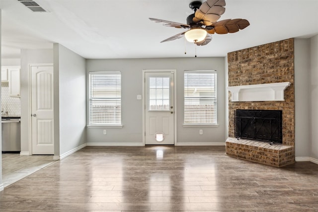 unfurnished living room with hardwood / wood-style flooring, ceiling fan, and a fireplace