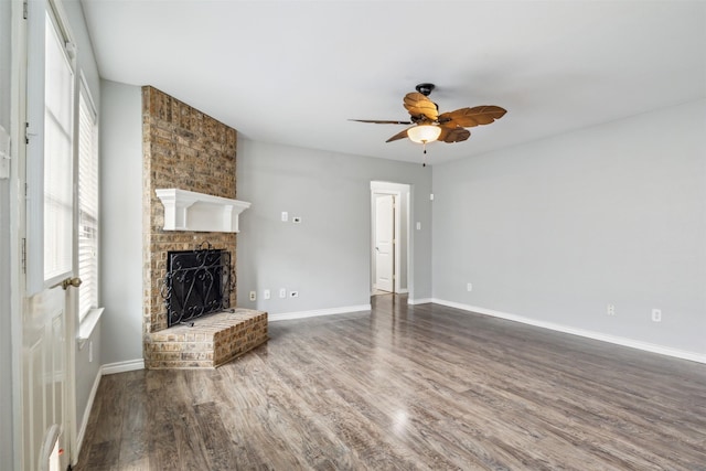 unfurnished living room featuring ceiling fan, wood-type flooring, and a brick fireplace