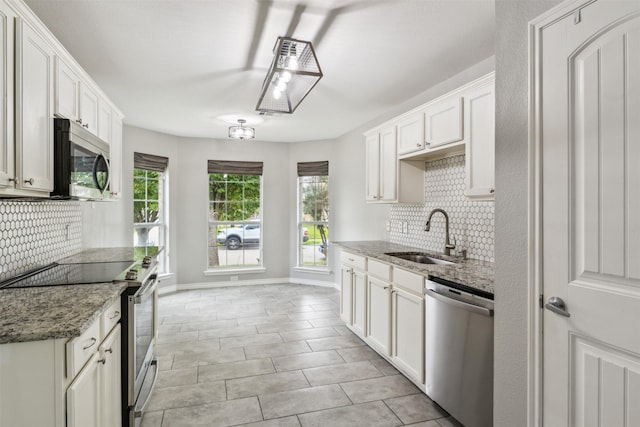 kitchen featuring stainless steel appliances, light stone countertops, sink, and white cabinets