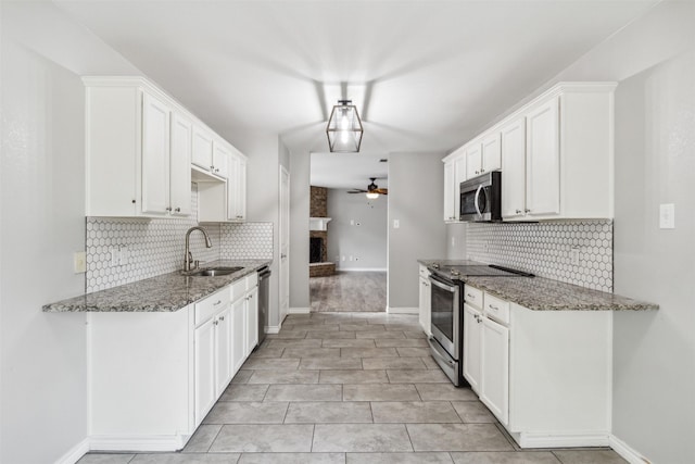 kitchen with white cabinetry, stainless steel appliances, sink, and dark stone countertops