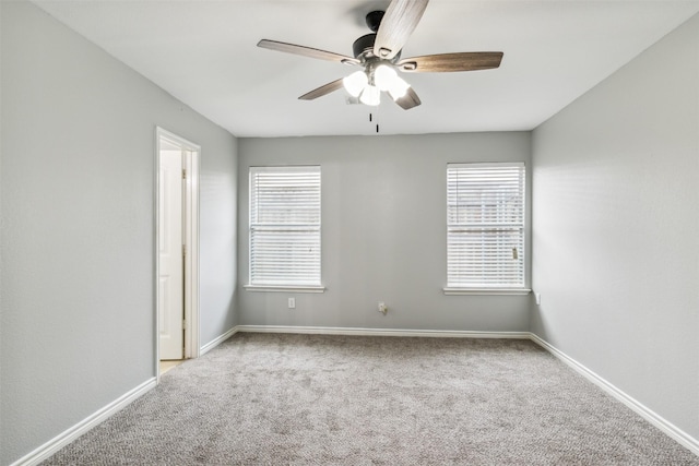 carpeted spare room featuring a wealth of natural light and ceiling fan