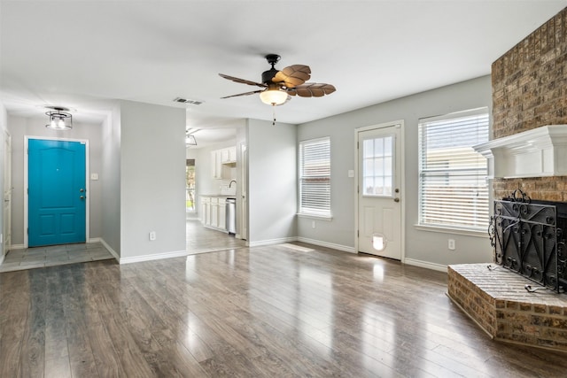 unfurnished living room with ceiling fan, dark hardwood / wood-style floors, sink, and a fireplace