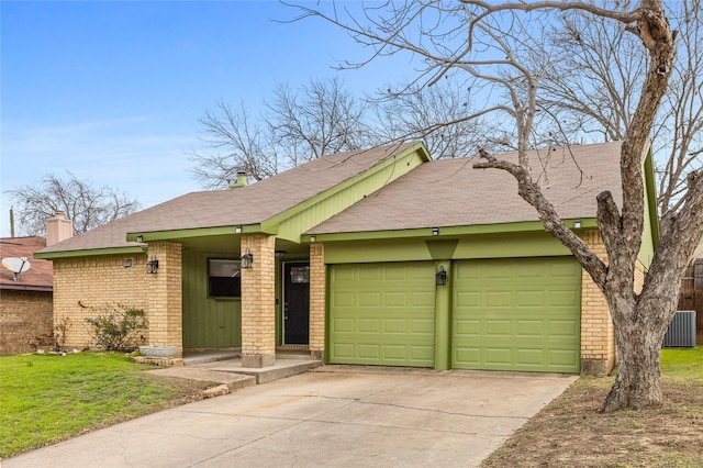 view of front of home with brick siding, an attached garage, central AC, driveway, and a front lawn