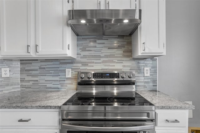 kitchen with electric range, ventilation hood, light stone countertops, and white cabinets