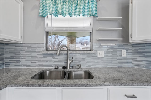 kitchen with stone counters, white cabinetry, sink, and tasteful backsplash