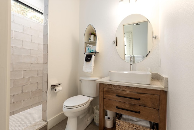 bathroom featuring tiled shower, vanity, and toilet