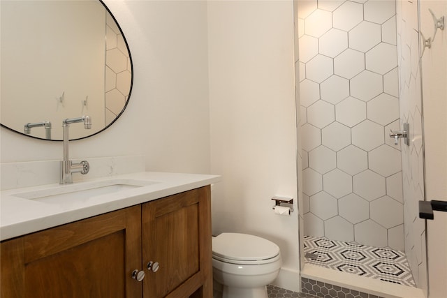 bathroom with vanity, toilet, and tiled shower