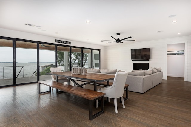 dining space featuring a water view, dark wood-type flooring, and ceiling fan