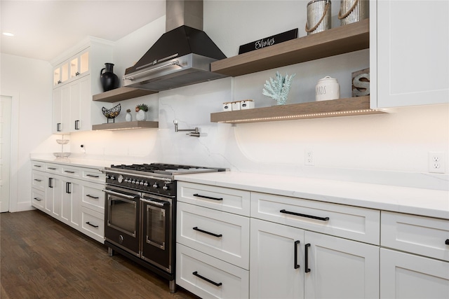 kitchen featuring white cabinetry, double oven range, range hood, and tasteful backsplash