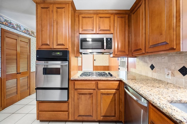 kitchen with stainless steel appliances, light tile patterned flooring, light stone countertops, and tasteful backsplash