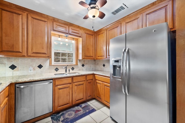 kitchen featuring light tile patterned flooring, appliances with stainless steel finishes, sink, decorative backsplash, and light stone counters