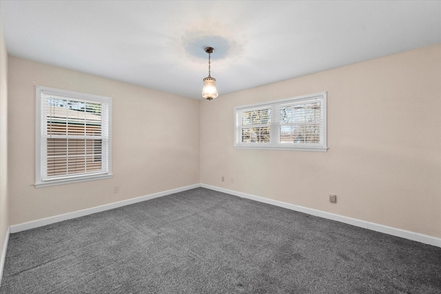 empty room with plenty of natural light and dark colored carpet