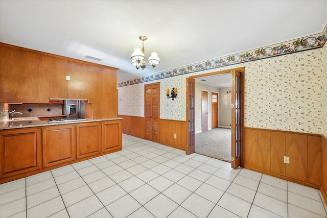 kitchen with sink, hanging light fixtures, a chandelier, kitchen peninsula, and stainless steel gas stovetop