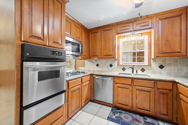 kitchen with sink, light stone counters, tasteful backsplash, light tile patterned floors, and stainless steel appliances