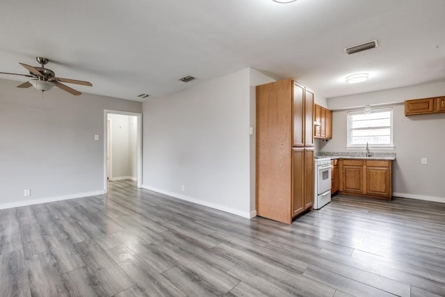 kitchen featuring ceiling fan, sink, light hardwood / wood-style floors, and white gas range oven