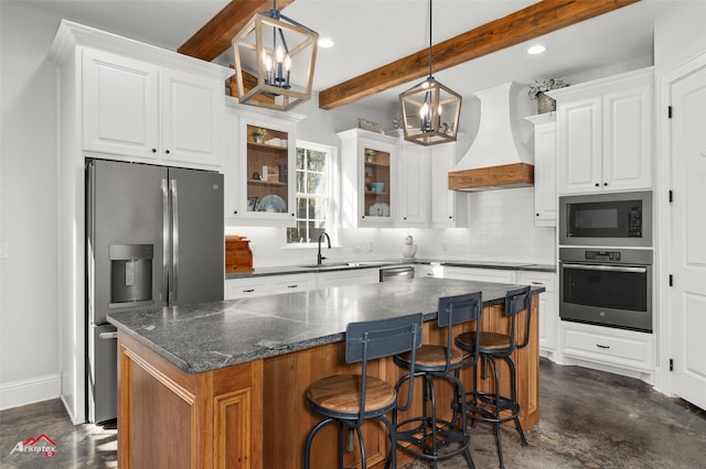 kitchen featuring appliances with stainless steel finishes, white cabinets, hanging light fixtures, a center island, and custom range hood