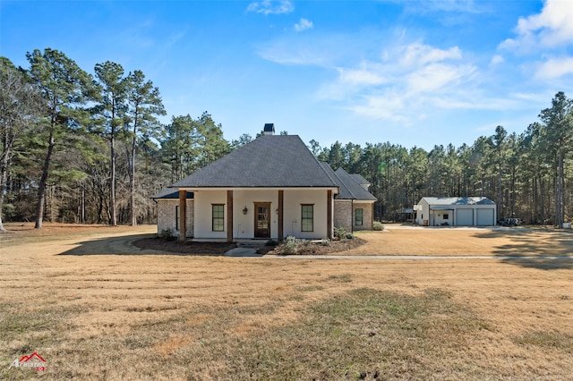 view of front of property featuring a garage, an outdoor structure, covered porch, and a front yard