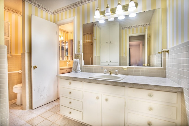 1225 Crestwood Dr, Cleburne, TX 76033 - bathroom featuring vanity, toilet, wainscoting, tile walls, and wallpapered walls