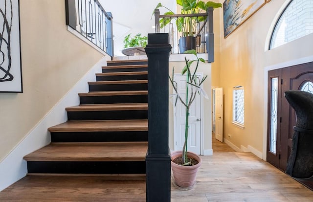 foyer entrance featuring a high ceiling, stairway, and light wood-style flooring