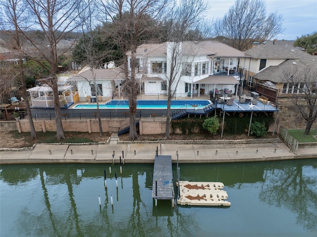 back of property with a fenced in pool, fence, a patio, and a water view