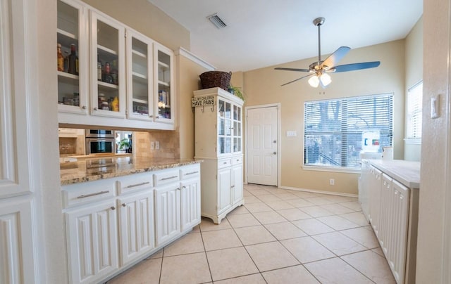 kitchen featuring light tile patterned floors, visible vents, decorative backsplash, glass insert cabinets, and white cabinetry