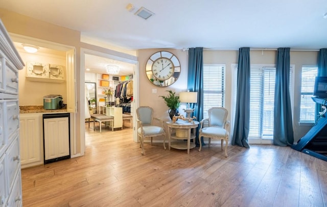 living area featuring light wood finished floors, visible vents, and a healthy amount of sunlight