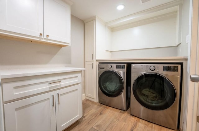 washroom with cabinets, light wood-type flooring, and independent washer and dryer