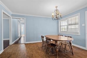 dining space featuring dark hardwood / wood-style flooring, crown molding, and a chandelier