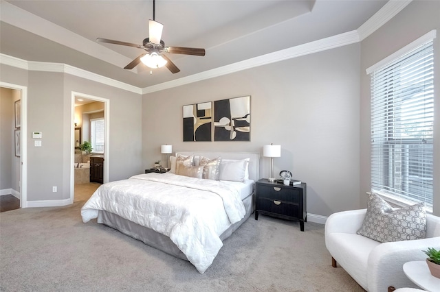 carpeted bedroom featuring ornamental molding, a raised ceiling, ceiling fan, and ensuite bathroom