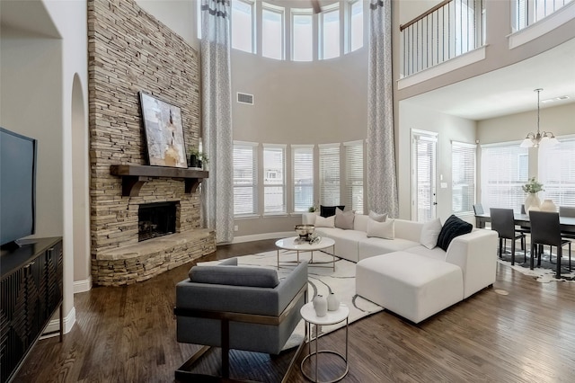 living room featuring hardwood / wood-style floors, a stone fireplace, a notable chandelier, and a healthy amount of sunlight