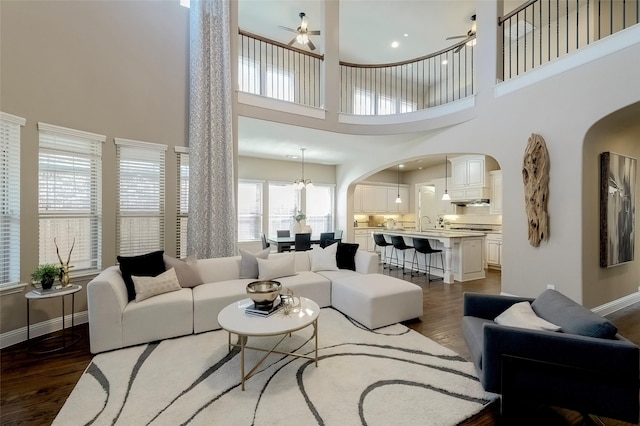 living room with ceiling fan with notable chandelier and dark wood-type flooring