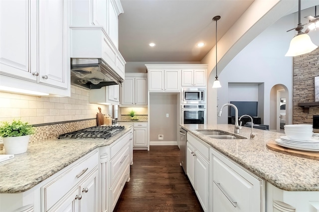 kitchen with appliances with stainless steel finishes, decorative light fixtures, sink, white cabinets, and light stone counters