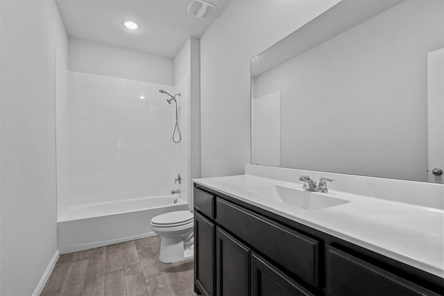 full bathroom with hardwood / wood-style flooring, vanity, tiled shower / bath, and toilet