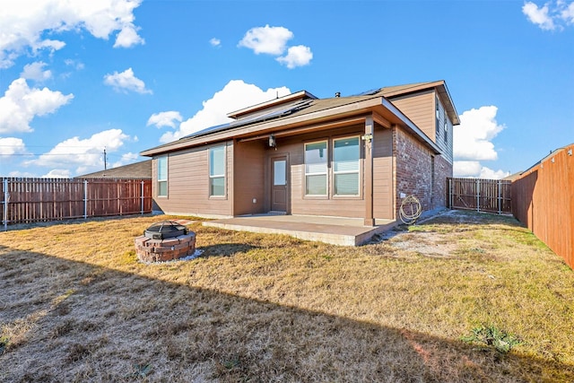 rear view of house featuring a patio area, a fire pit, and a lawn