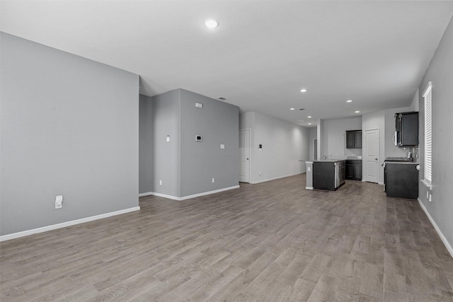 unfurnished living room featuring hardwood / wood-style flooring and sink