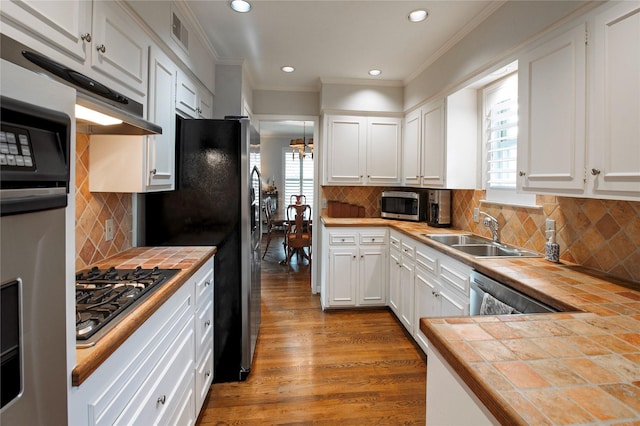 kitchen featuring sink, tile countertops, ornamental molding, appliances with stainless steel finishes, and white cabinets