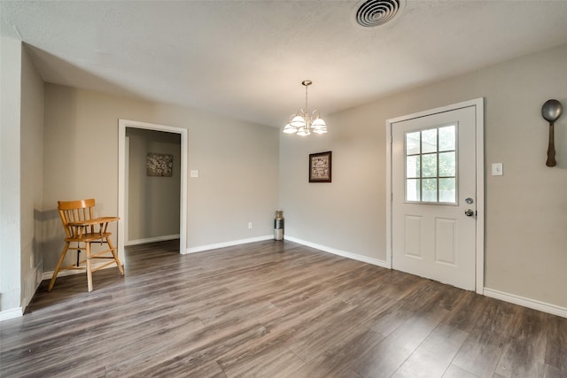 interior space with hardwood / wood-style floors, a textured ceiling, and an inviting chandelier